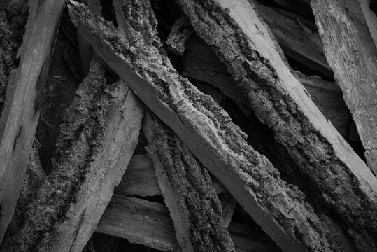 Black and white close-up of messy pile of raw wooden scraps with bark.