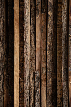 Stacked raw wooden planks with live edge bark background.