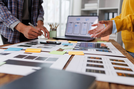 Ux ui designers collaborating on mobile app wireframe development, planning creative workflow, brainstorming new application features, and prototyping user interfaces