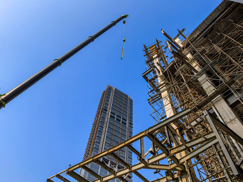 High-rise building construction with heavy machinery mobile crane lifting materials and scaffolding framework