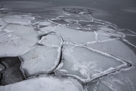 Abstract texture of broken ice floes on the sea surface. Natural geometric patterns of frozen water in winter, Nordic coastal landscape.