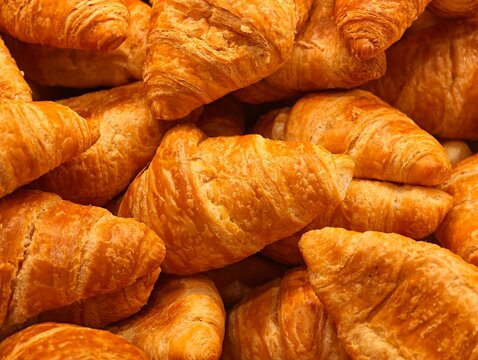 Close-up stacked golden flaky croissants.