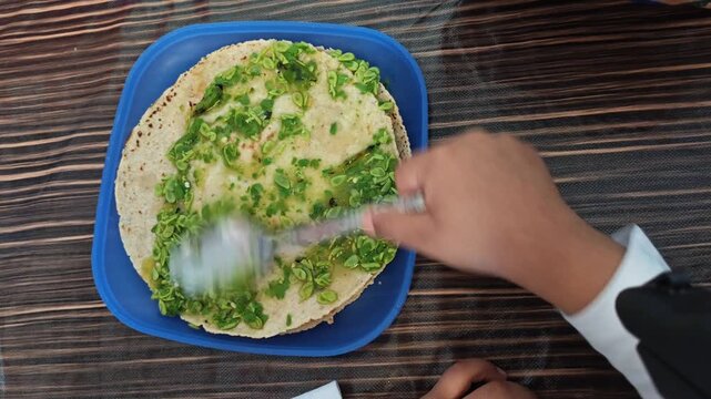 Spreading Green Guaje Salsa over Corn Tortilla