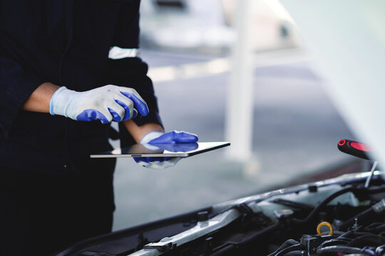 Close Up of Mechanic Recording Vehicle Inspection Results on Digital Tablet During Automotive Maintenance Service in Professional Repair Garage