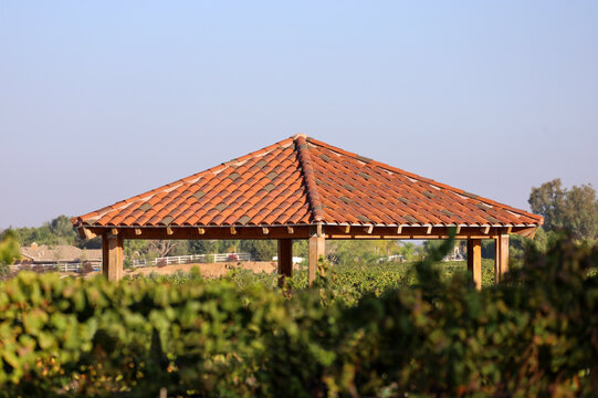 View of a wooden gazebo with two tone classic terracotta Spanish clay tile roof.