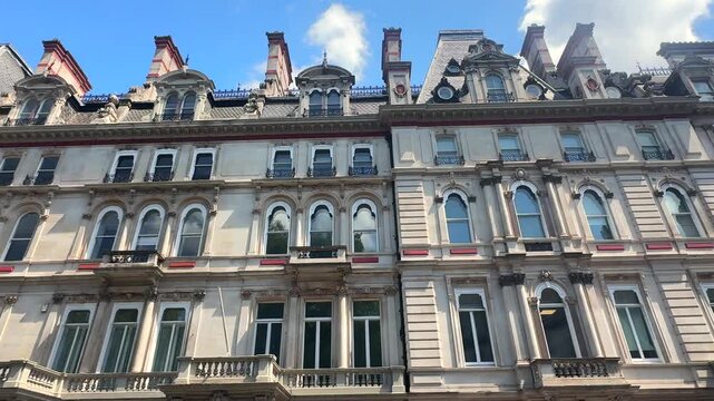An elegant stone facade features dormer windows and decorative balconies under blue sky