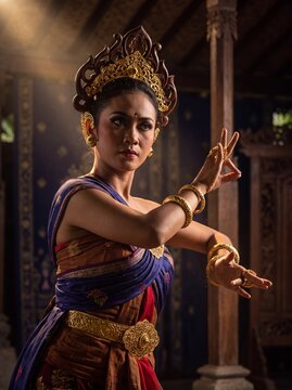 Balinese dancer performing graceful mudras in dramatic gold and indigo light.