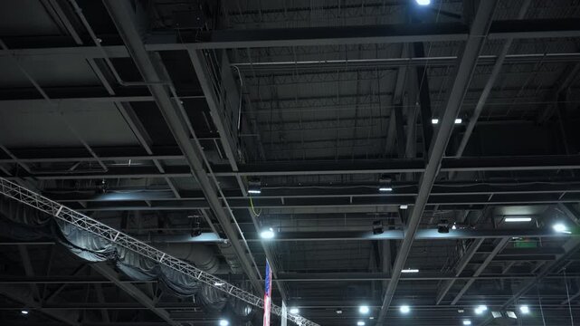 Black Metal roof trusses and ceiling structure inside a large hall or center. Industrial steel framework supporting lighting, ventilation, and event equipment.