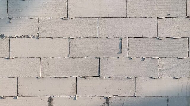 Photo of cement walls with brick blocks. Shadows, black, dark, grey, gray. Side view. Copy space, background, text, product mockup.  grain, grainy. sunlight, sunrise, sunshine.