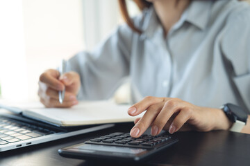 Doing finance, budgeting and tax calculation concept. Woman using calculator to calculate financial...