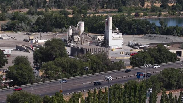 Aerial of industrial facility and highway I90 near Yakima Washington with silos and aggregate storage piles