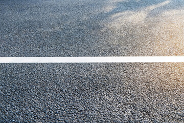 Fototapeta premium A close-up view of a dark asphalt road surface with a bright white lane marking, showing road texture.