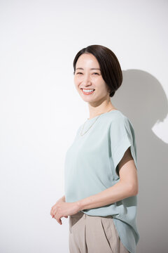 白背景で半袖で笑顔で立つ日本人女性の上半身 明るく親しみやすい働く女性のイメージ　カメラ目線