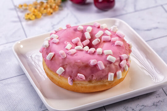 Pink frosted donut with mini marshmallows on white plate