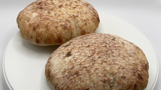 Studio shot of two pita bread loaves rotating on white background.