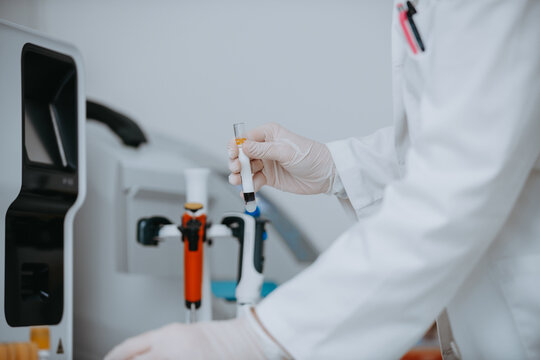 Scientist in White Coat Holding Test Tube With Sample in Modern Medical Laboratory Research Setting
