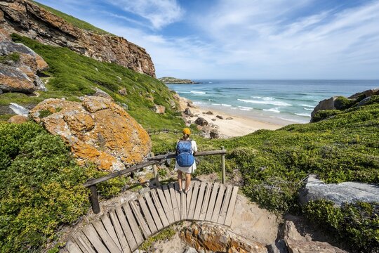 Young pretty woman wearing dress off coast and sea at Robberg Nature Reserve, Plettenberg Bay, South Africa
