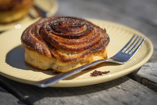 Cinnamon roll and fork lie on a light yellow plate, Houvig, Ringk&oslash;bing Fjord, Denmark