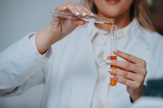 Female Scientist Pouring Orange Liquid Between Test Tubes in Lab Close-Up Hands and Experiment