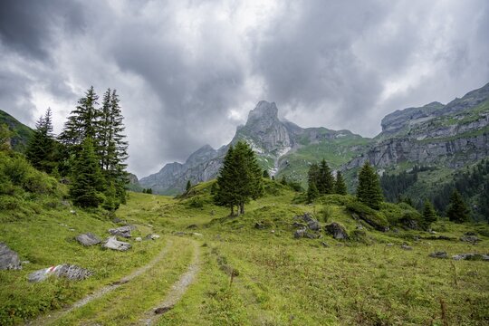 Hiking trail in a valley, rocky peak Spaltenhorn, mountain landscape with dark clouds, Bernese Alps, Bernese Oberland, Switzerland