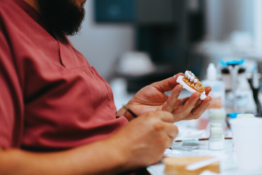 Dental Technician Hand Finishing Ceramic Crowns In A Dental Lab Workshop With Precision Tools