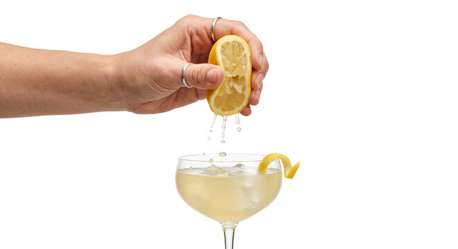 Hand squeezing fresh lemon juice into a refreshing cocktail with ice and garnish