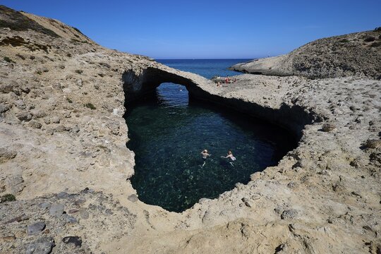 Two swimmers under a natural rock bridge in turquoise water, Kapras, Kapros, Beach, Kapros Beach, Caves, Paralia Kapros, Milos, Cyclades, Greek Islands, Greece