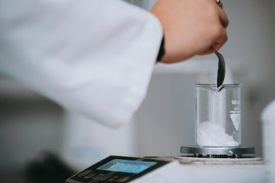 Laboratory Scientist Weighing White Powder In Glass Beaker On Electronic Scale For Analysis
