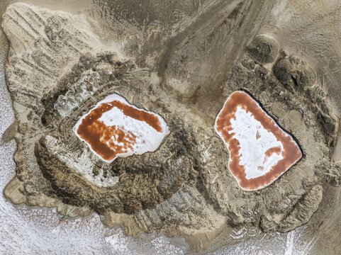 Saline ponds with ruddy algae growth and white salt deposits at the Skeleton Coast. Aerial view. Drone shot. Namib Desert, Dorob National Park, Namibia