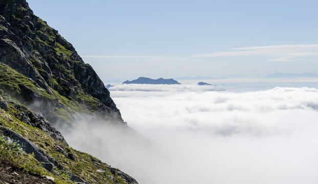 Mountain peaks above the clouds, mountain landscape and sea, view from the summit of Stornappstinden, Lofoten, Nordland, Norway