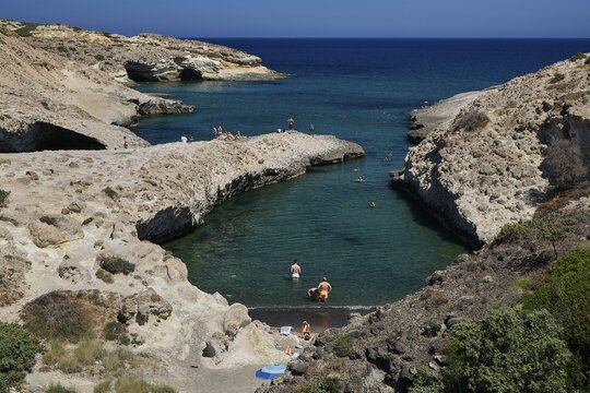 People swim in a sheltered bay with rocky shore and turquoise water, Kapras, Kapros, Beach, Kapros Beach, Caves, Paralia Kapros, Milos, Cyclades, Greek Islands, Greece