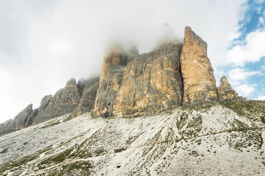 Dramatic misty Tre Cime di Lavaredo area. Dynamic clouds after rain move over the rugged limestone peaks of the Italian Dolomites. Three sisters circular loop popular trail summer