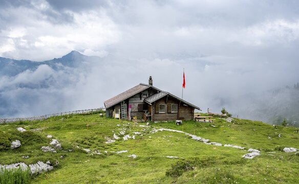 Small mountain hut Suls-Lobhornh&uuml;tte with Swiss flag, cloudy mountain landscape, Bernese Alps, Bernese Oberland, Switzerland
