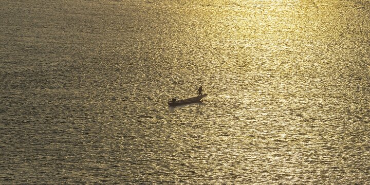 Fisherman with longtail boat (Thai: Ruea Hang Yao) at sunrise, Mekong between Thailand and Laos