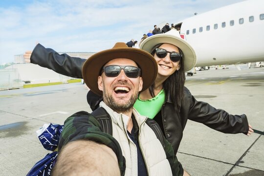 Smiling happy man woman passengers taking selfie photo on departure by commercial aircraft background boarding plane runway tarmac summer vacation departure flight transit aviation travel tourism