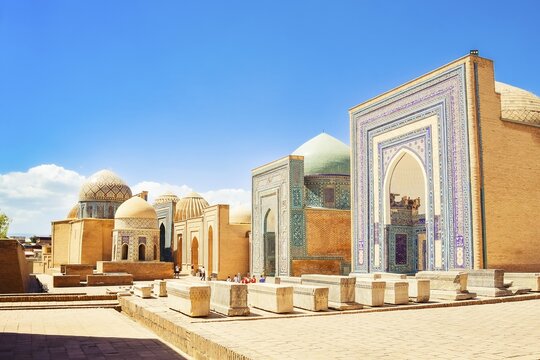 Cinematic Shah i Zinda necropolis in Samarkand. Visitors explore the stunning blue-tiled mausoleums and turquoise domes of historic UNESCO Silk Road landmark