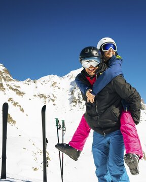 Young caucasian couple pose hug enjoying looking at snowy mountains range in winter. Get away skiing holidays lifestyle. Tetnuldi ski resort viewpoint. Caucasus mountains high altitude freeriding
