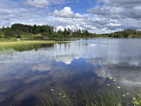A quiet lake under a cloudy sky, with clear water reflections and surrounding meadows, Dalsland Canal, Dalsland, Sweden
