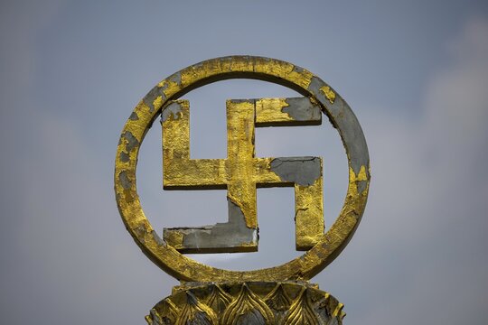 Golden swastika symbol in traditional Buddhist form, symbol of luck, protection and the cosmic order of Buddha's teaching, the circular bezel and lotus ornaments emphasize purity and spiritual perfection. Chee Chin Khor Temple, Bangkok, Thailand