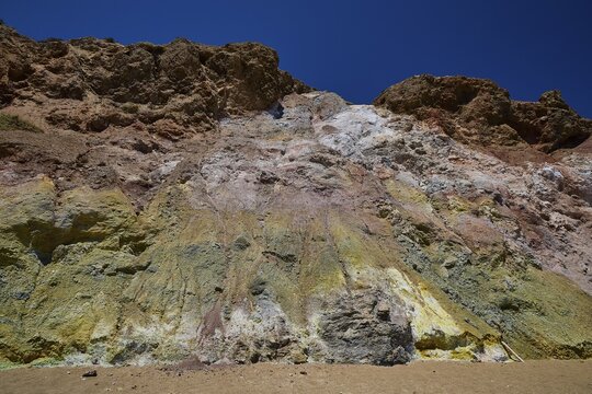 Colourful rock wall under clear blue sky, with various eroded layers, Paliochori beach, Paliochori, volcanic rock, copper, nickel, mineral salts, volcanic island, Milos, Cyclades, Greek islands, Greece