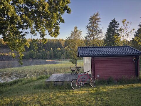 Little red hut with bike on a lake. wooden terrace in quiet, green forest, camping, vacation, H&ouml;gsbyn, H&ouml;gsbyn, Dalsland Canal, Mellerud Municipality, Sweden