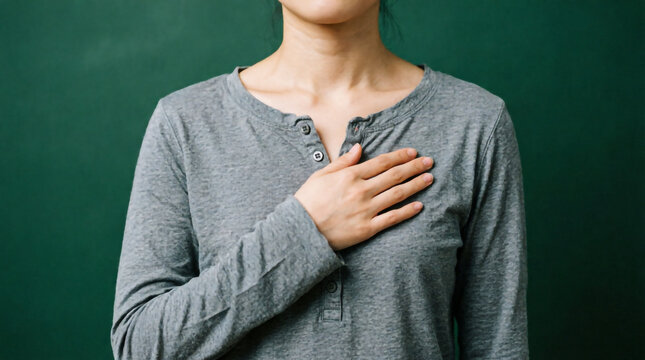 Person with hand on chest conveys sincerity and reflection through expressive body language gesture.