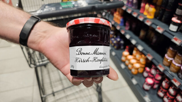 Hand holding bonne maman cherry jam in supermarket