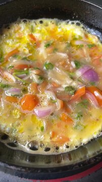 Spicy egg omelette being prepared with green chili and onion at home for breakfast in Dhaka, Bangladesh. Traditional homemade cooking with fresh ingredients.