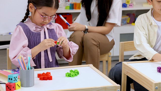 Young Girl with Glasses Building Math Block Tower in Classroom