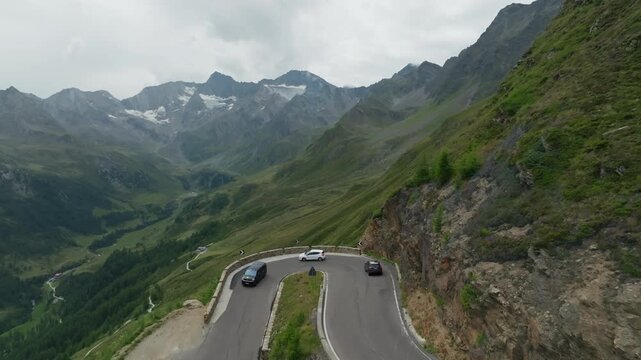 Drone view of a car traveling on the Timmelsjoch High Alpine Road in Tyrol Austria passing breathtaking alpine landscapes and dramatic mountain peaks