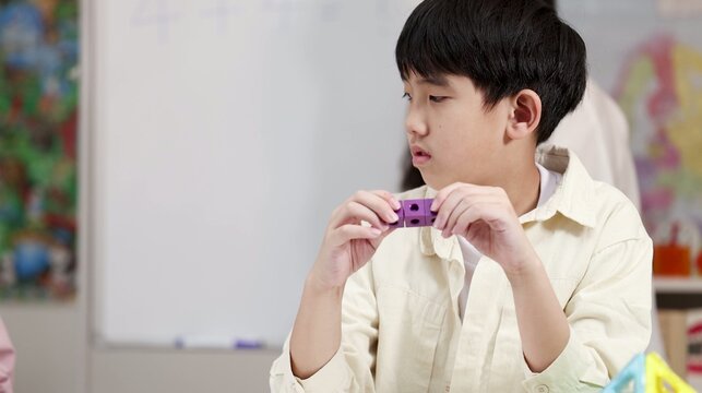 Young Asian Boy Concentrating on Linking Cubes in a Preschool Classroom