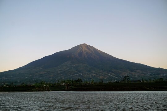 Majestic view of Mount Cikuray in Garut with a calm lake water surface in the afternoon.