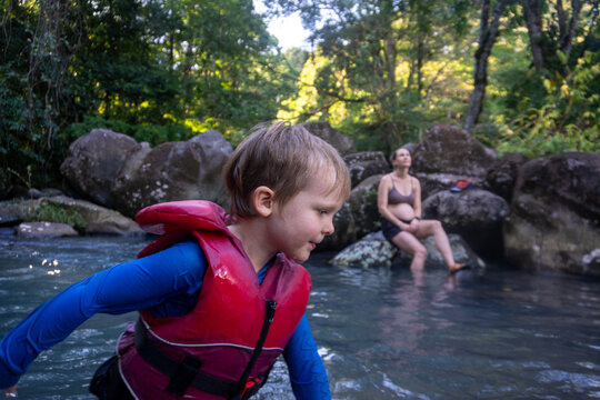 Young boy in a life vest playing in a river