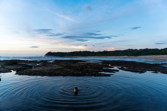 Person swimming alone in a tidal pool at dusk